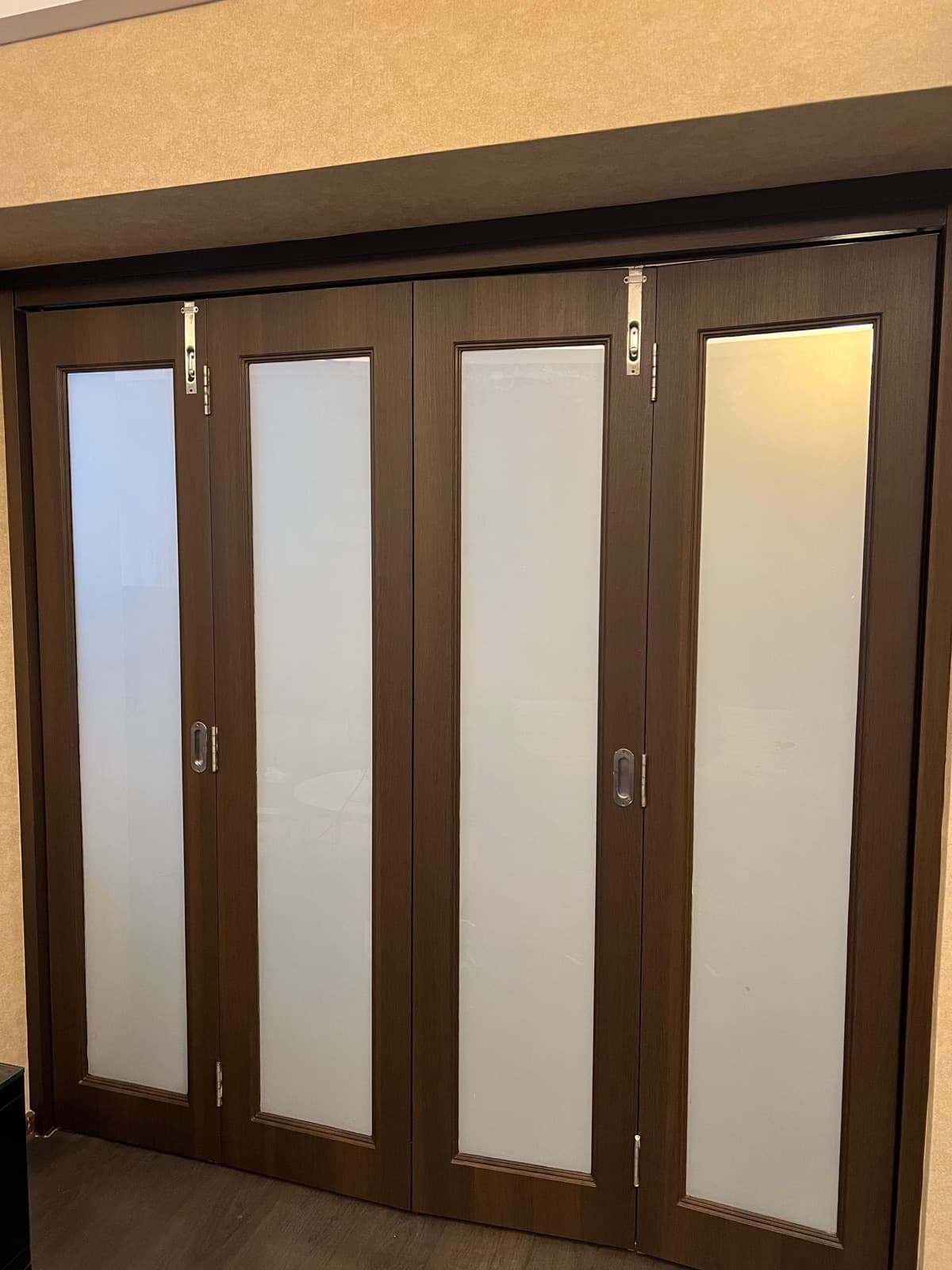 Bi-fold doors wrapped in dark wood-grain with frosted glass panels