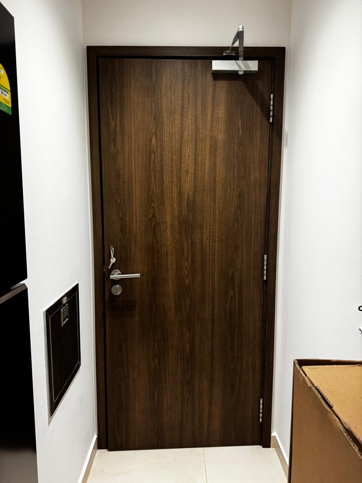 Condo main door wrapped in vertical walnut wood-grain architectural film